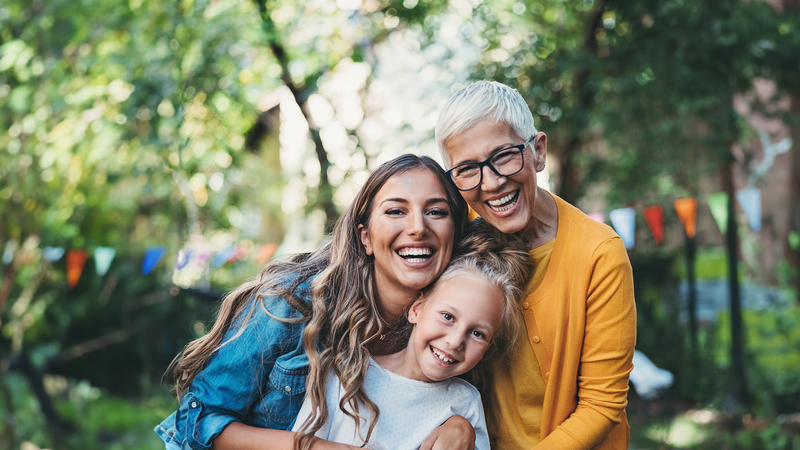 Weibliche Personen aus 3 Generationen auf einen Gartenfest blicken strahlend in die Kamera.