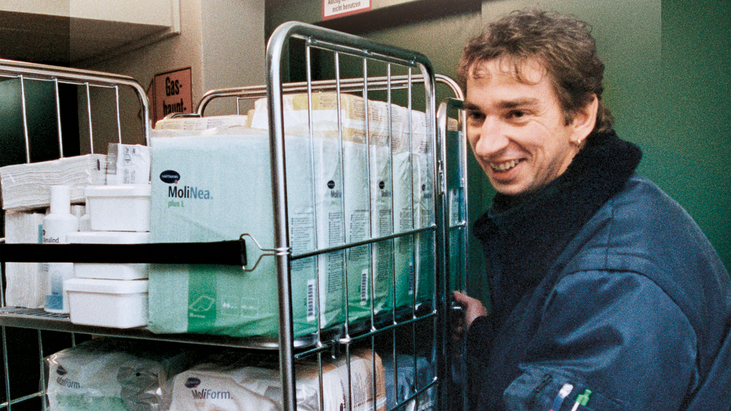 Mann schiebt einen Rollcontainer mit HARTMANN-Produkten