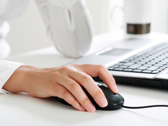 Hand liegt auf Computermaus, daneben eine Tastatur