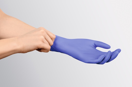 Hand ohne Handschuh zieht der anderen Hand einen blauen nitrile Handschuh an.