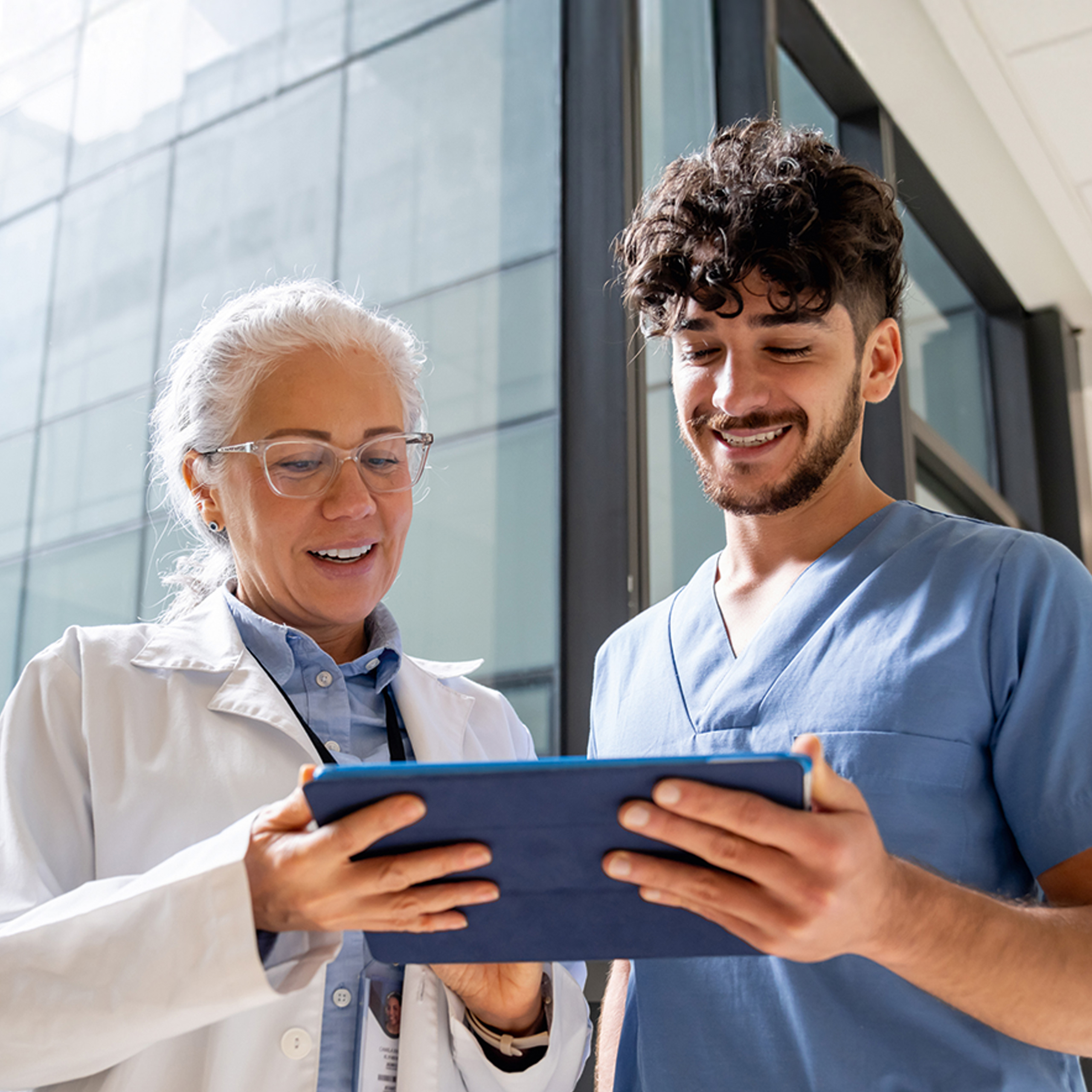 A doctor and a nurse looking at patient information together on a tablet.