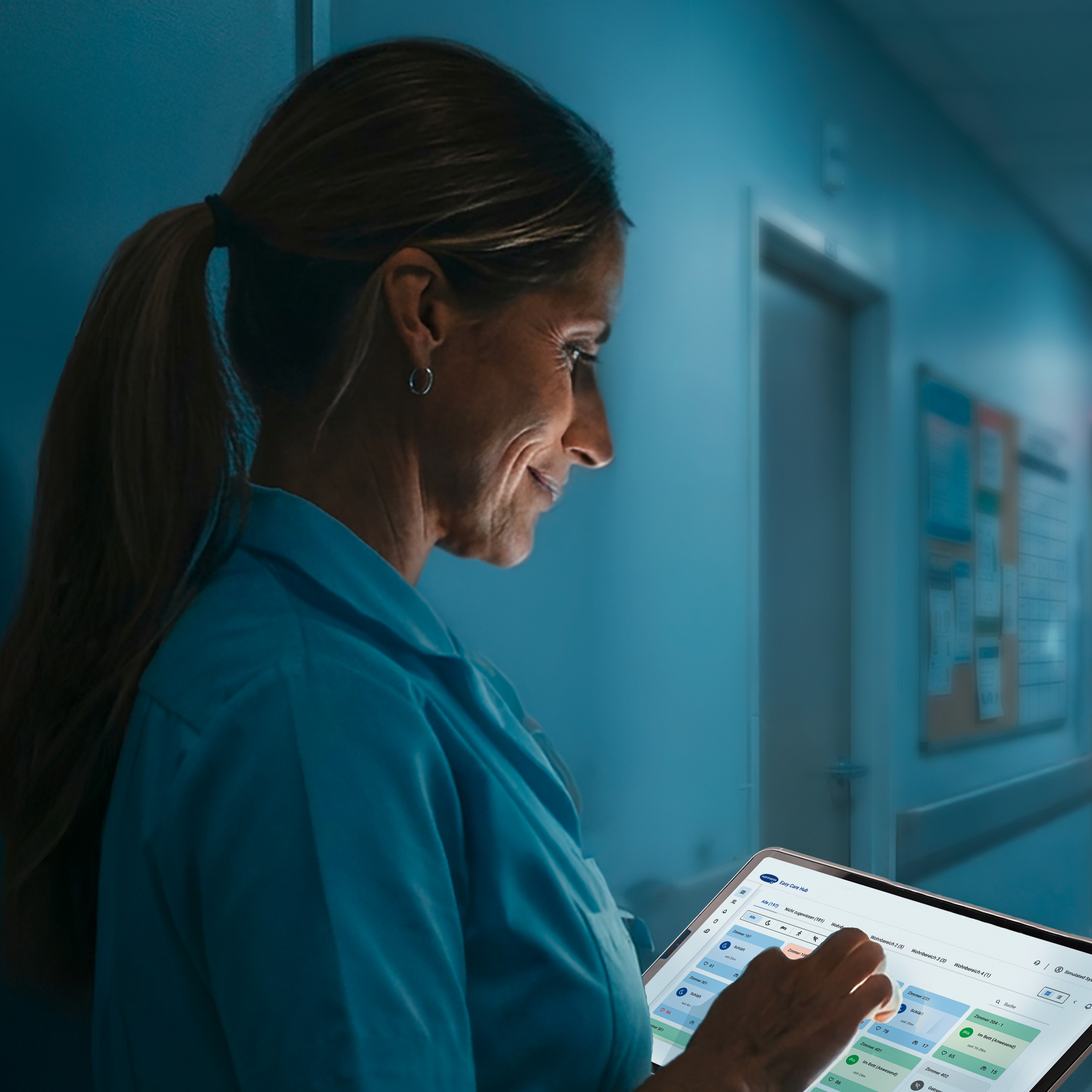 doctor in a dark room looking at a glowing digital device.