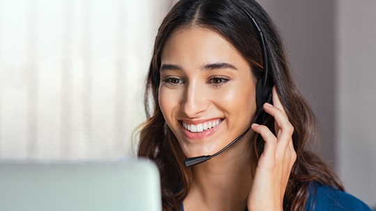 Frau mit Headset schaut in einen Laptop