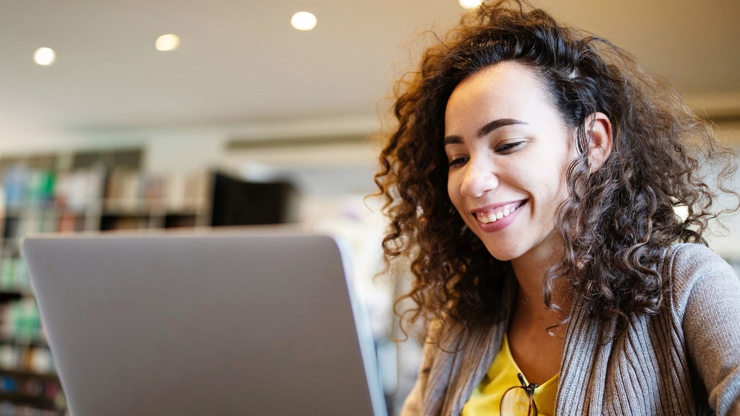 Genç bir kadın dizüstü bilgisayarının başında oturuyor.