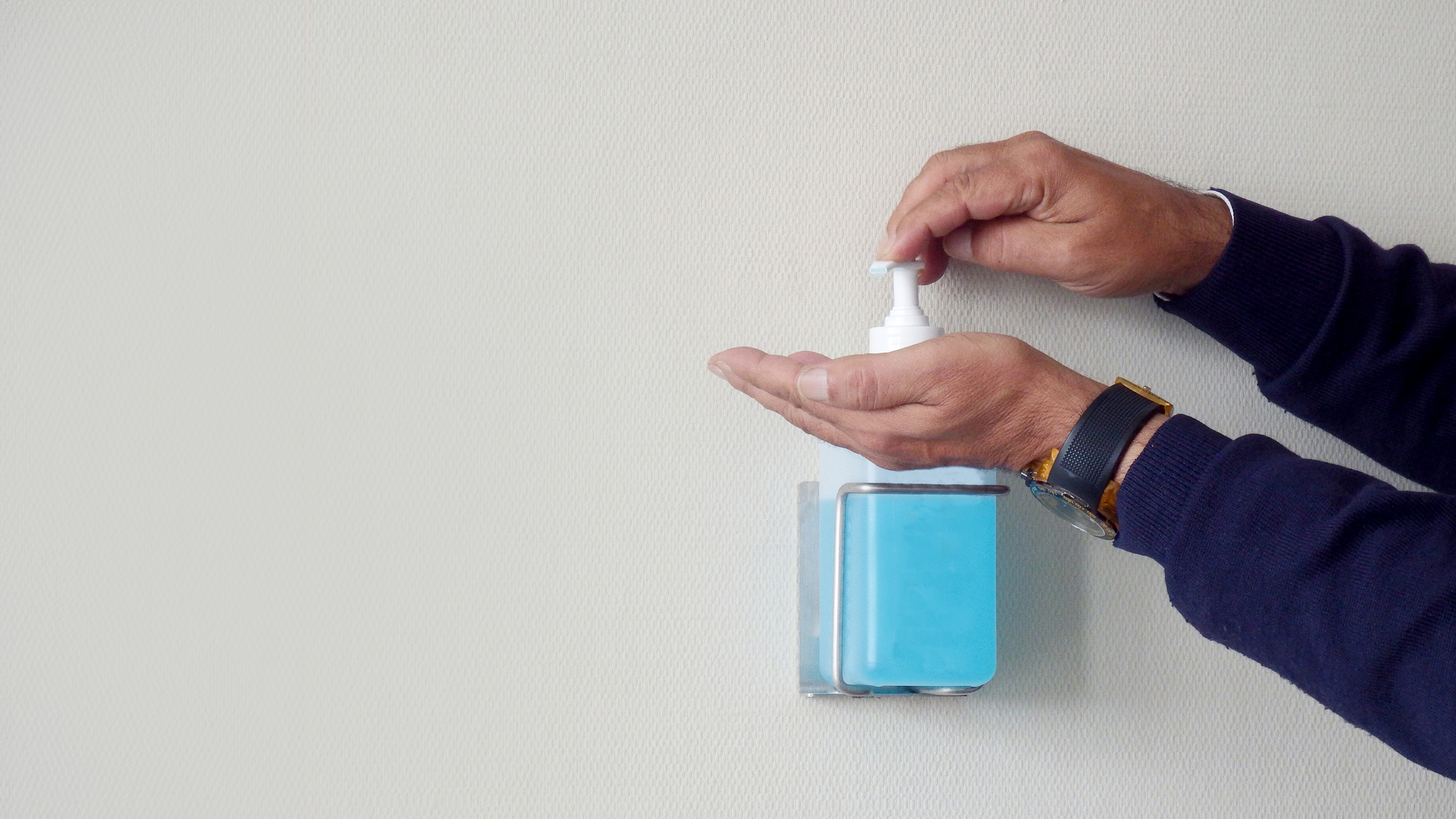 Male hands using a disinfectant pump.