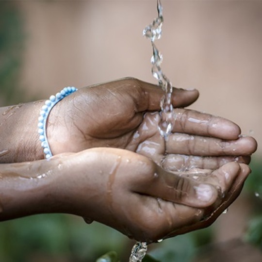 Someone holds their hands under a spray of water and catches it in their palms.