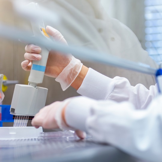 Ein Labormitarbeiter verwendet eine Pipette, um etwas in eine Reihe von Reagenzgläsern zu injizieren.