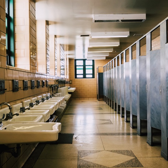 A public restroom with a row of sinks on the left and cubicles on the right.
