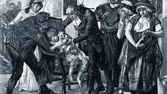 Historic black-and-white drawing of Edward Jenner vaccinating a child in front of a group of people.