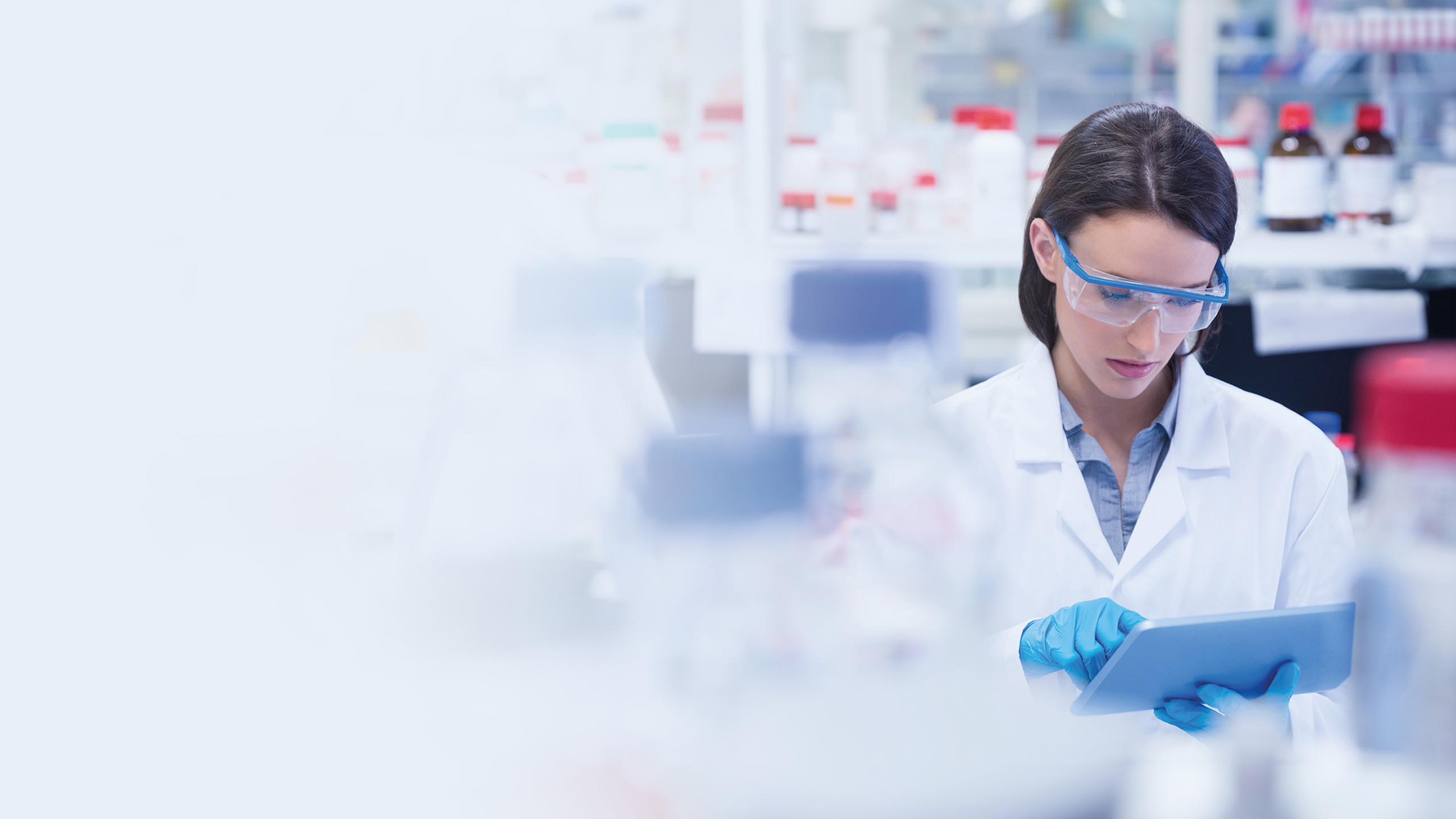 A scientist in a lab checks something on a clipboard.