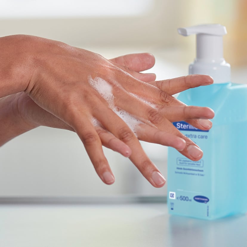 Close up of hands washing in front of a Sterillium® bottle