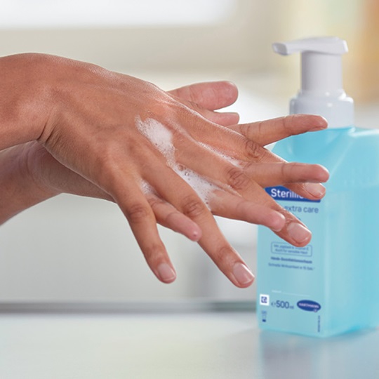 Close up of hands washing in front of a Sterillium® bottle