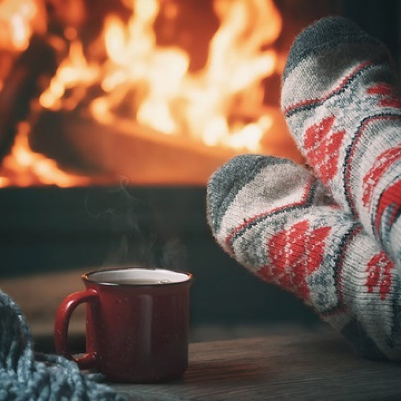 Feet in thick woolen socks in front of a fireplace.