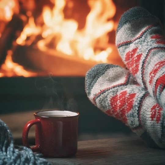Feet in thick woolen socks in front of a fireplace.