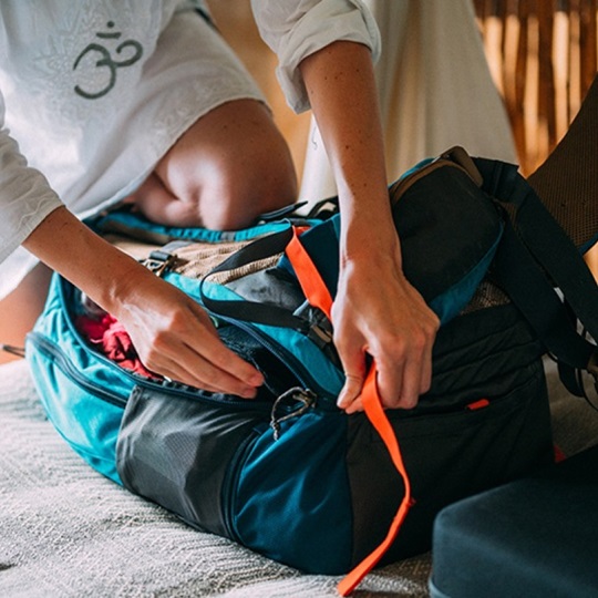 A woman packs a travel backpack.