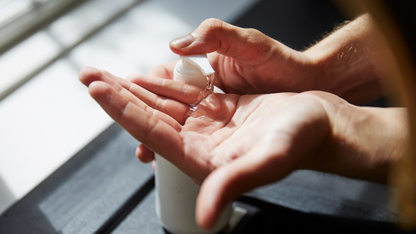 Someone uses disinfectant dispensers to disinfect their hands.