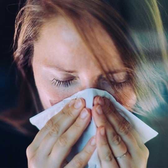 Woman blowing her nose.