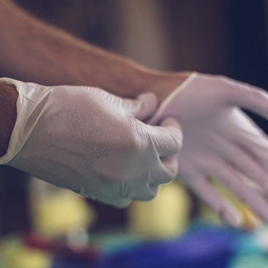 Nahaufnahme von Händen, die sterile Handschuhe anziehen