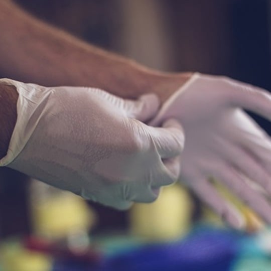 Nahaufnahme von Händen, die sterile Handschuhe anziehen
