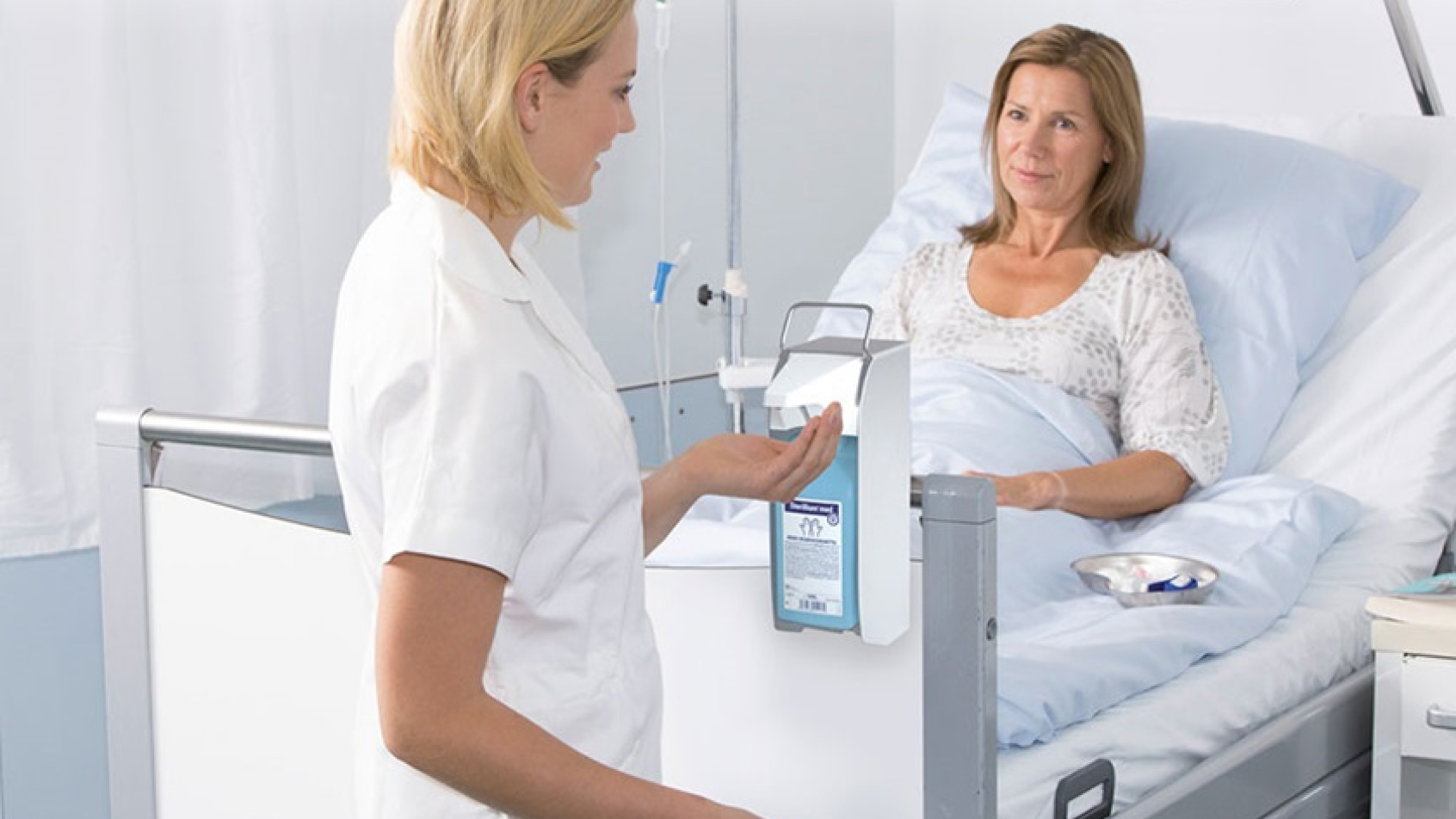 Hand disinfection at the point of care: Nurse applying disinfectant before approaching patient.