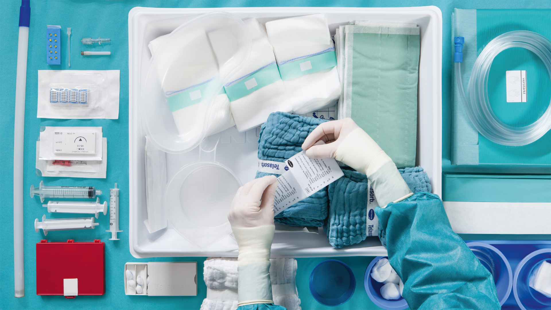  A surgical kit with bandages, tubes, syringes, and other medical essentials, arranged neatly in a sterile environment, with a gloved hand handling packaging.