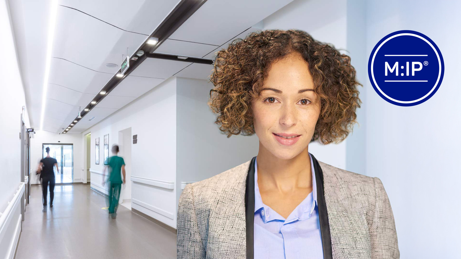  Smiling professional woman in a modern hospital corridor with blurred staff in the background, symbolizing efficient healthcare services.