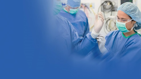 Doctors in an operating room putting on gloves and wearing surgery attire