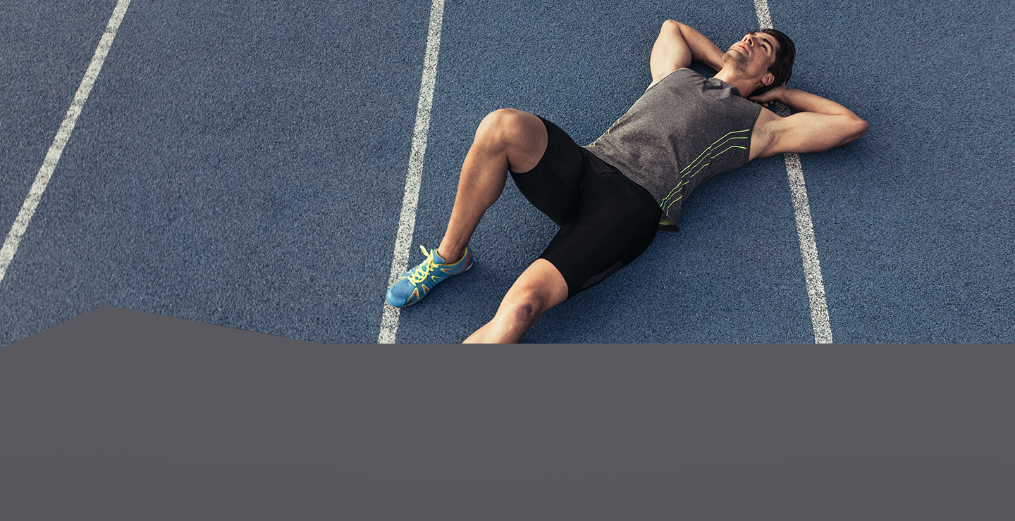 Mladý muž ve sportovním ležící na běžecké dráze.