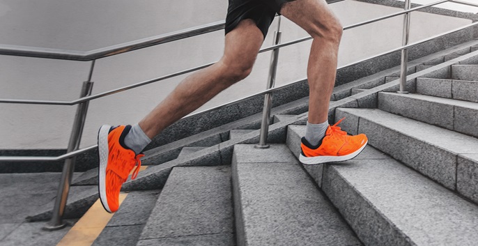 Man with orange sports shoes running up stairs.