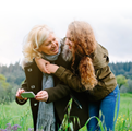 personal healthcare; grandmother and daughter hugging and smiling in a green field