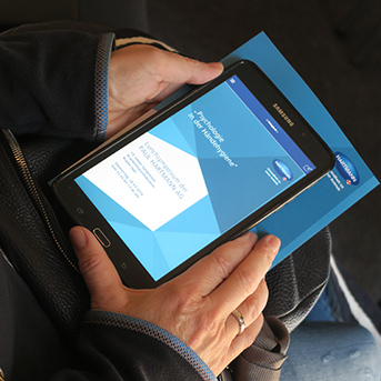 Hand hält Tablett mit Ulmer Symposium App