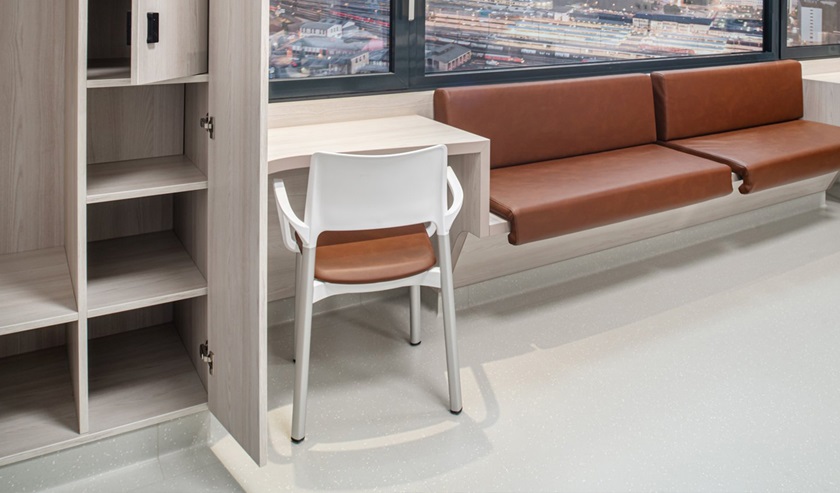 Visitors’ area with deep bench and a table and chair for each patient.
