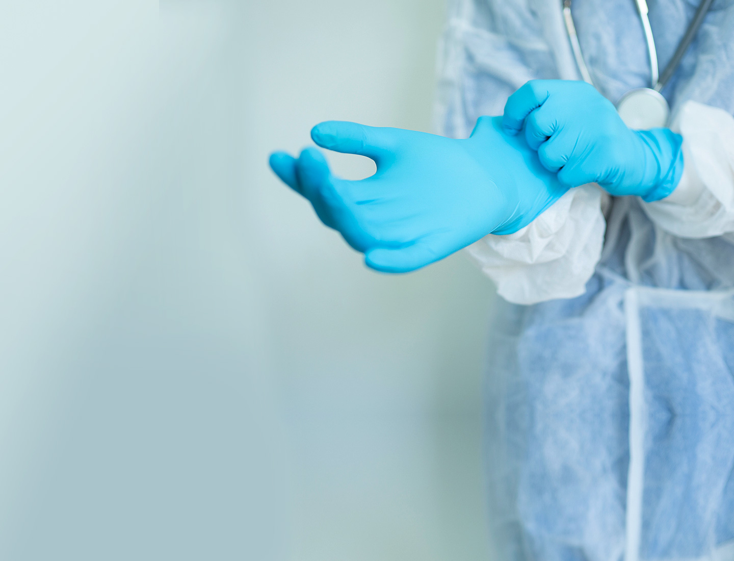 Nurse in full protective clothing putting on surgical gloves
