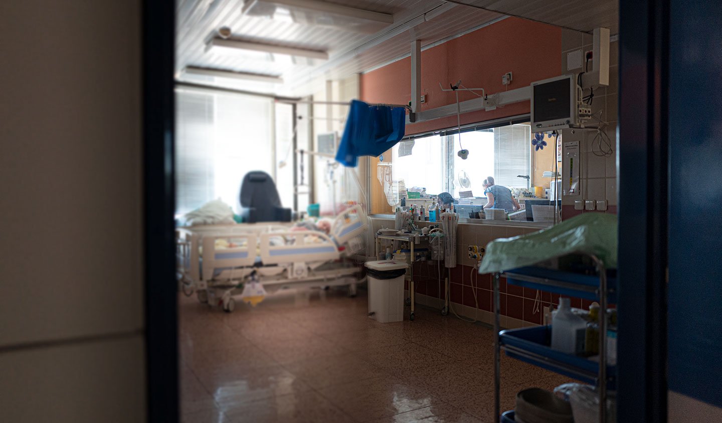 View into hospital room with patient in bed and nurse standing nearby