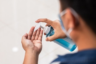 Man with mouth-nose protection disinfects his hands