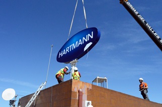 Inštalácia veľkého loga HARTMANN v modrom ovále na strechu budovy s pomocou žeriava je dôkazom, že akvizícia spoločnosti Lindor v Španielsku dopadla dobre.