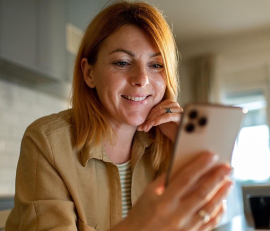 Frau schaut lachend auf ihr Smartphone