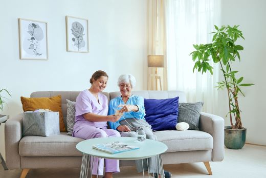 Pflegerin mit Dame auf Sofa