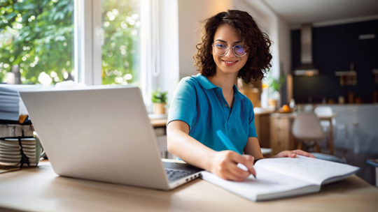 Frau beim E-Learning am Laptop mit Block