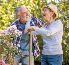 älteres, lachendes Ehepaar im Garten mit Spaten