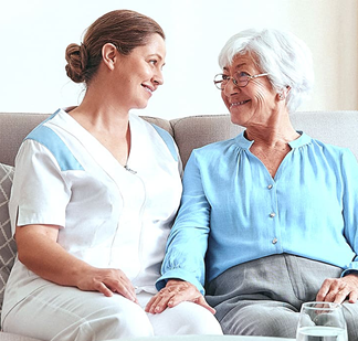 Pflegerin mit Seniorin auf Sofa