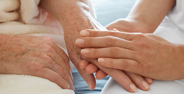 Patient en zorgprofessional houden elkaars handen vast