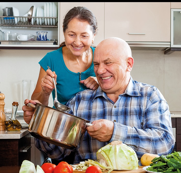 Senior hält Kochtop in der Hand und Frau hilft beim Auffüllen