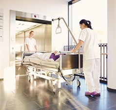 Krankenschwestern schieben Bett in Aufzug