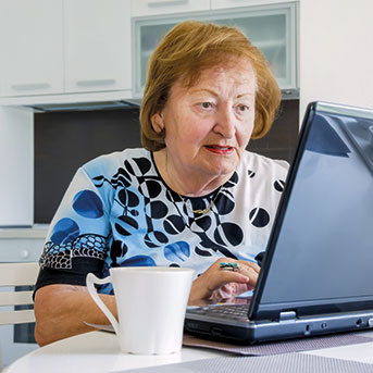 Seniorin sitzt vor Laptop