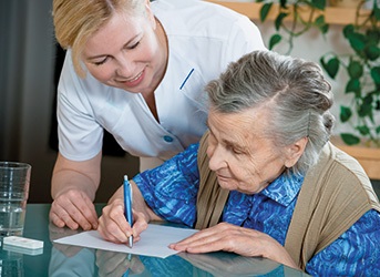Pflegerin hilft Seniorin etwas zu unterschreiben