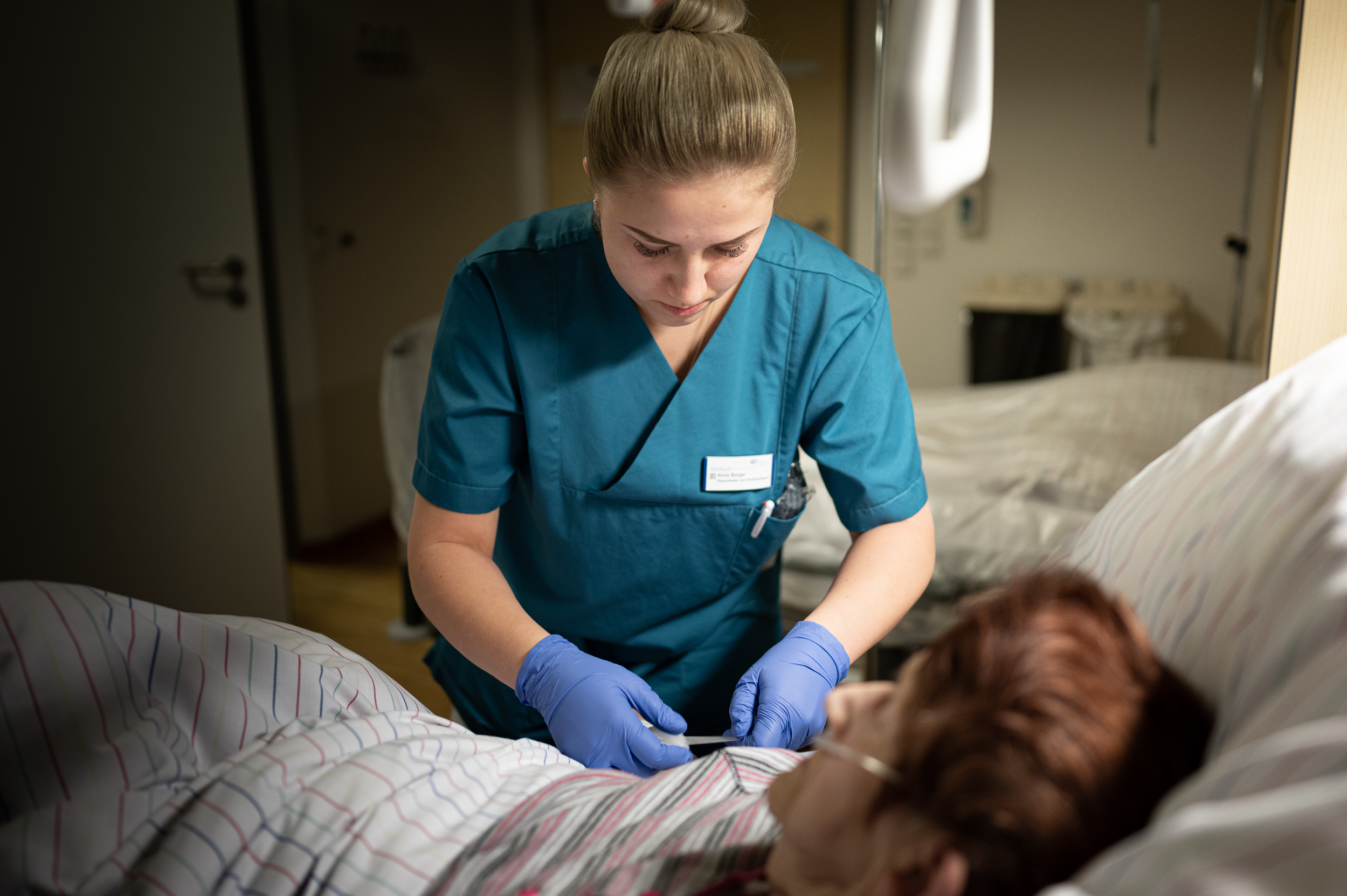 Krankenschwester fixiert den Zugangsschlauch einer Patientin