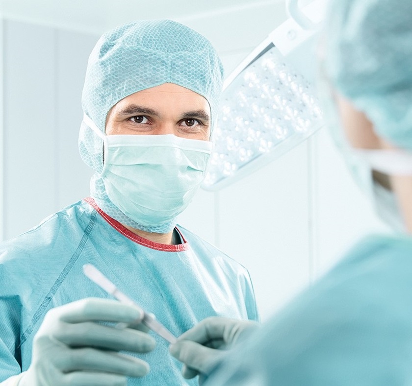 un médecin en vêtement de travail passe un scalpel à un autre médecin, lors d'une opération