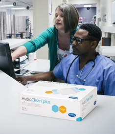 Hydroclean sitting on a counter with medical staff doing administrative work behind it