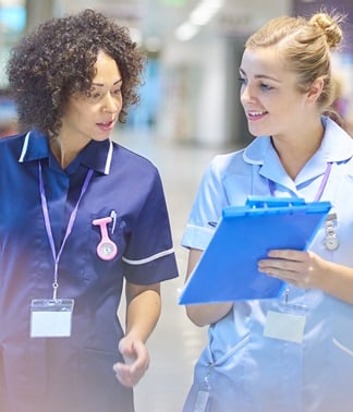 Two nurses discussing the medical information on a clip board